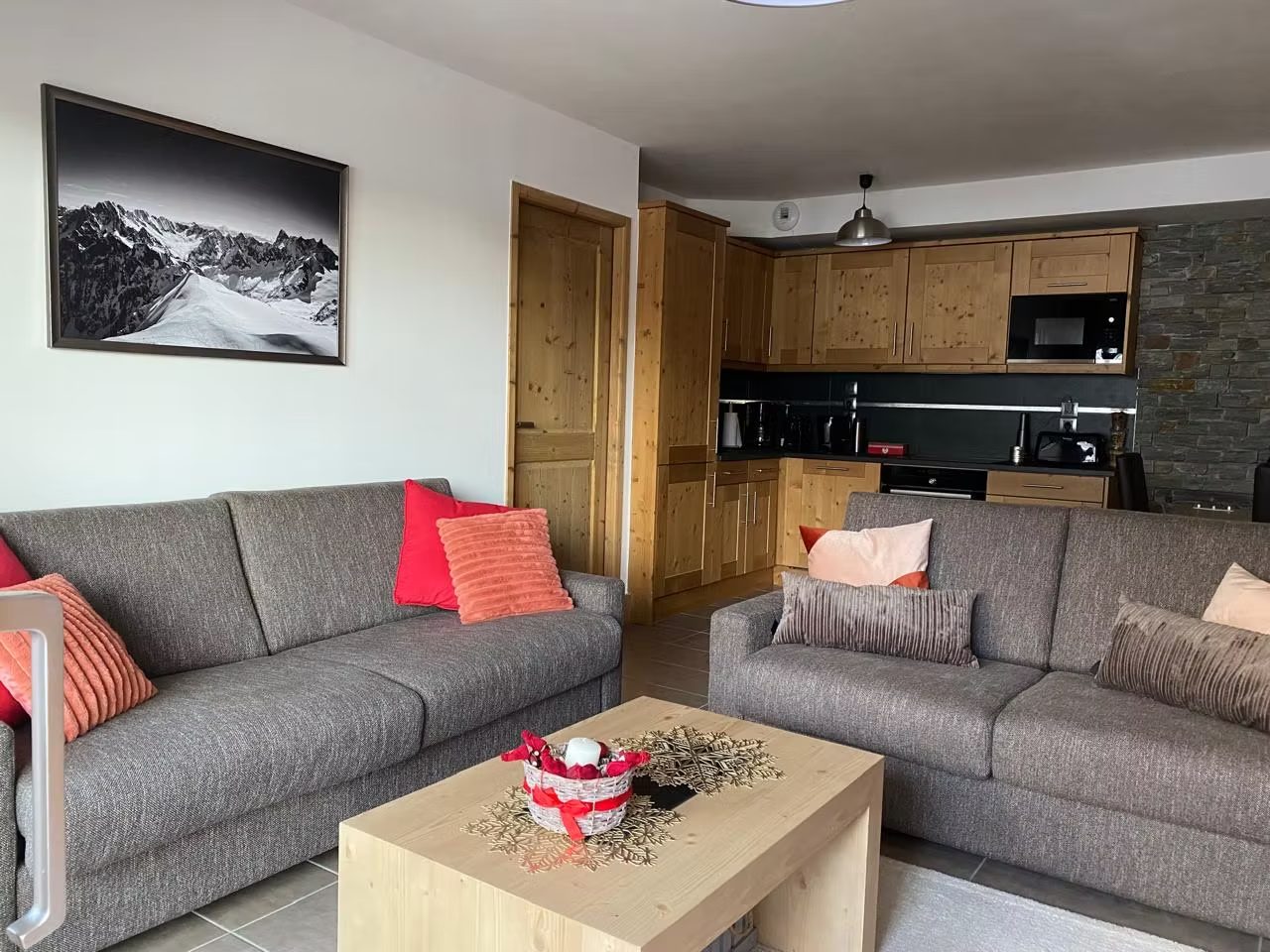 Séjour chaleureux de l'appartement à Valmorel : deux canapés, cuisine en bois massif, photo du Mont Blanc au mur